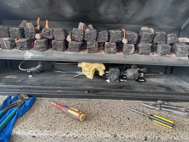Gas fire being serviced with tools